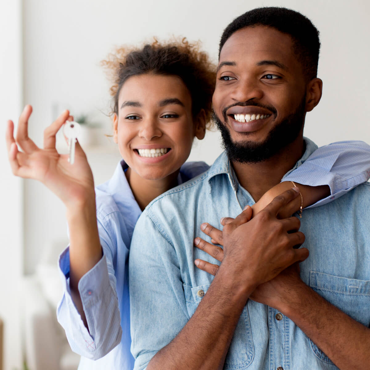 Happy couple embracing and holding key to their new home after moving in.